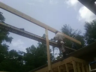 Carpenter setting a ridge beam over a new addition frame — Ice Dam Removal by Roofing Brothers in Malta